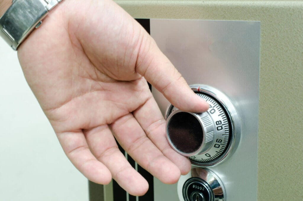 A Hand Turning The Dial On A Mechanical Combination Safe