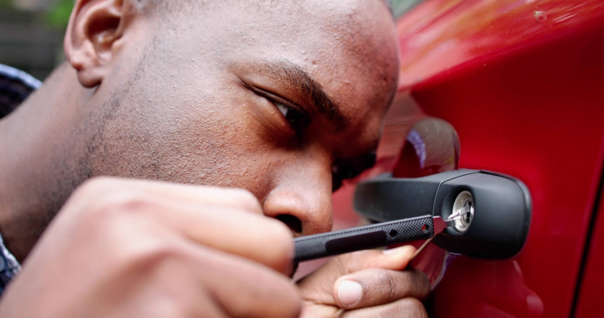 A locksmith working on a car door lock with a lock pick