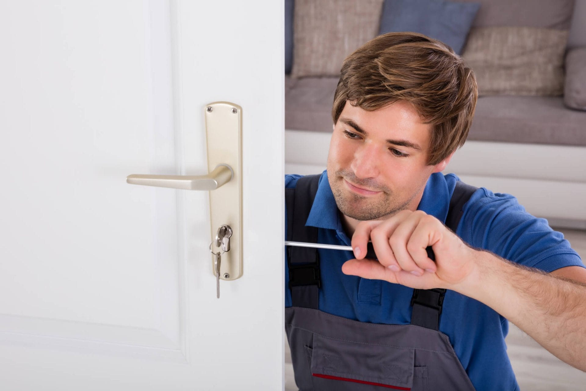 A locksmith working on a door lock with a screwdriver