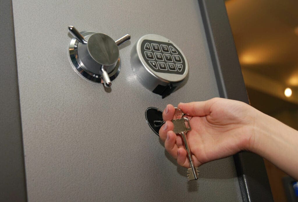 A person holding a key in front of an electronic safe