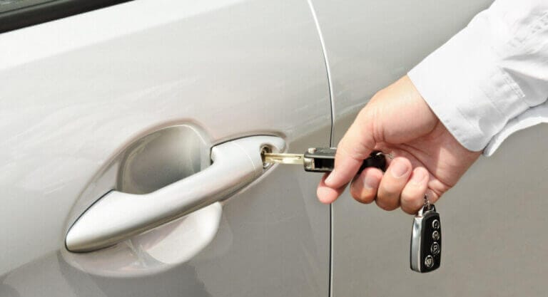 A Person Inserting A Key Into A Car Door Lock