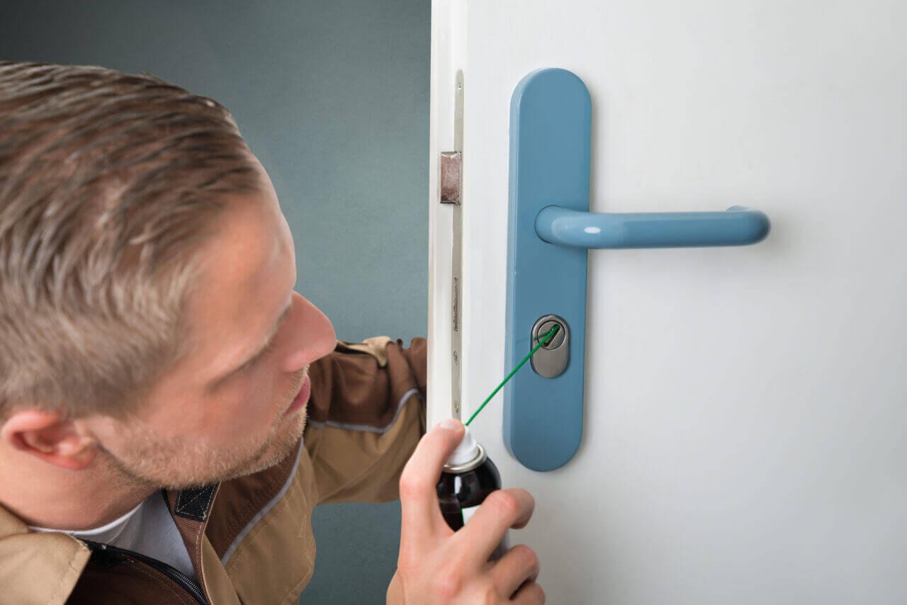 A person lubricating door lock