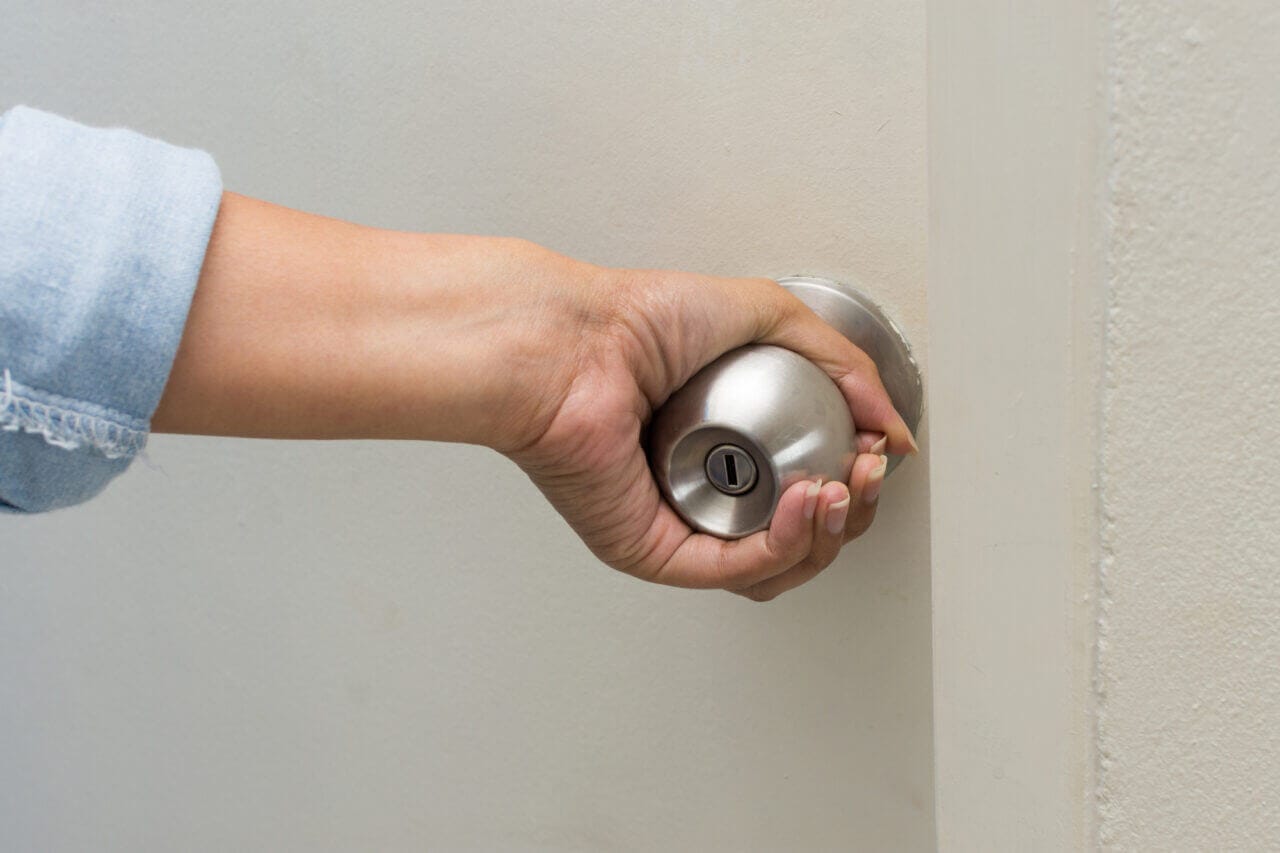 A person opening a deadbolt door lock