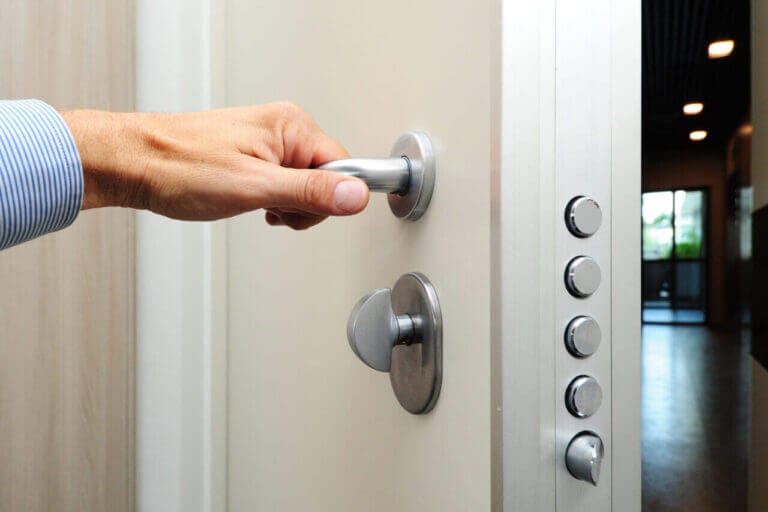 A Person Opening A Door With A High Security Lock