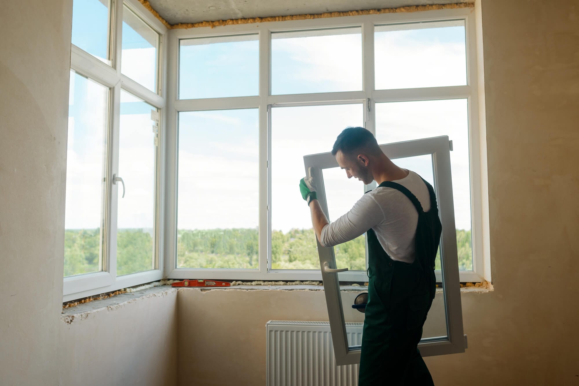 A technician holding a large window sash next to windows