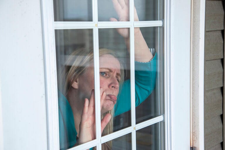 A troubled person behind a window stuck close