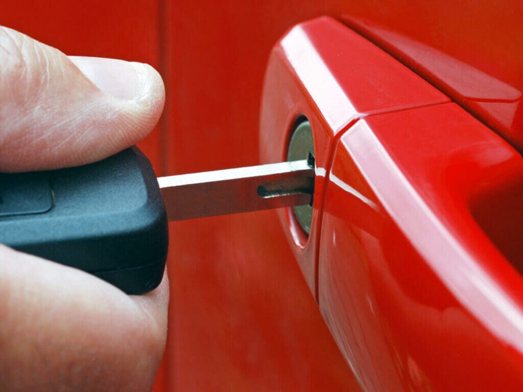 Close Up Of A Hand Inserting A Key In A Car Door Lock