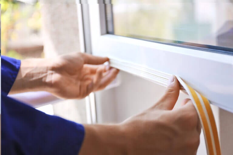 Close up of a person installing foam tape weatherstripping on a window