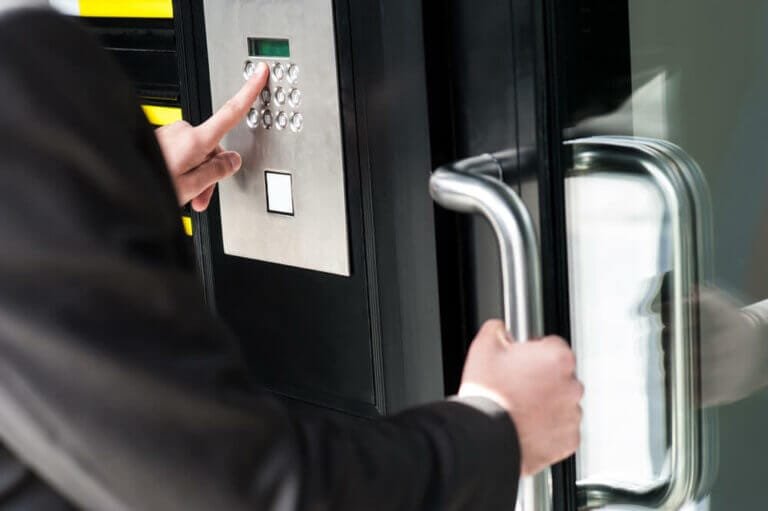 A Person Entering Security Code On A Door Keypad Lock